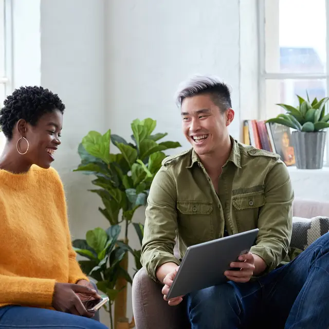 Two people discussing information on a tablet and smiling