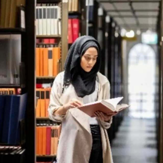 A woman is reading in a library.