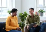 Two people discussing information on a tablet and smiling